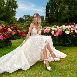 Eine schöne blonde Frau (wie Dornröschen) posiert in einem weissen Brautkleid mit Brautschuhen von Cinderellas_by_Marcela in ivory-Farbe in einem wunderschönen Rose-Garten.