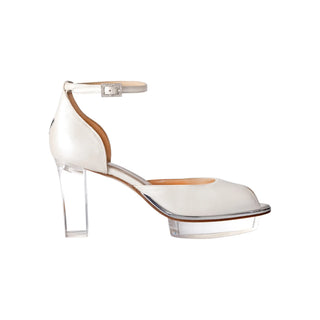 Ein zauberhafter Brautschuh als Opentoe Riemchenpump von der Firma Cinderella’s by Marcela in Ivory/Perlfarbe mit elegantem Nuss-Logo (als Inspiration aus dem Märchen drei Nüsse für Aschenbrödel) sowie hochwertigem transparenten Absatz und Plateau. Die Schuhe sind mit silbernen Accessoires verziert, und die Schnalle ist mit funkelnden Steinchen veredelt. Perfekt geeignet für Hochzeiten sowie alle gehobene Events.