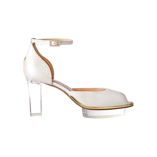 Ein zauberhafter Brautschuh als Opentoe Riemchenpump von der Firma Cinderella’s by Marcela in Ivory/Perlfarbe mit elegantem Nuss-Logo (als Inspiration aus dem Märchen drei Nüsse für Aschenbrödel) sowie hochwertigem transparenten Absatz und Plateau. Die Schuhe sind mit goldenen Accessoires verziert, und die Schnalle ist mit funkelnden Steinchen veredelt. Perfekt geeignet für Hochzeiten sowie alle gehobene Events.