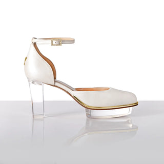 Ein zauberhafter Brautschuh als Closetoes Riemchenpump von der Firma Cinderella’s by Marcela in Ivory/Perlfarbe mit elegantem Nuss-Logo (als Inspiration aus dem Märchen drei Nüsse für Aschenbrödel) sowie hochwertigem transparenten Absatz und Plateau. Die Schuhe sind mit goldenen Accessoires verziert, und die Schnalle ist mit funkelnden Steinchen veredelt. Perfekt geeignet für Hochzeiten sowie alle gehobene Events.