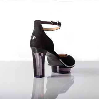 Cinderellas schwarze Riemchenpumps Abendschuhe. Ein zauberhafter Abendschuh als Closetoe Riemchenpump von der Firma Cinderella’s by Marcela in schwarzen Wildleder mit elegantem Nuss-Logo (inspiriert aus dem Märchen drei Nüsse für Aschenbrödel) sowie hochwertigem transparentem schwarzen Absatz und Plateau. Die Schuhe sind mit silbernen Accessoires verziert, und die Schnalle ist mit funkelnden Steinchen veredelt. Perfekt geeignet für Galas, Bälle, rote Teppiche und gehobene Events.