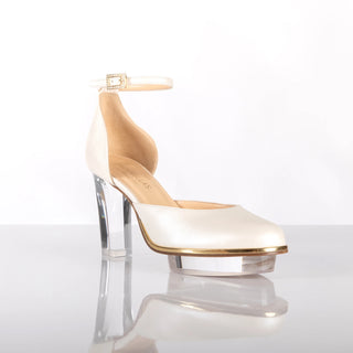 Ein zauberhafter Brautschuh als Closetoes Riemchenpump von der Firma Cinderella’s by Marcela in Ivory/Perlfarbe mit elegantem Nuss-Logo (als Inspiration aus dem Märchen drei Nüsse für Aschenbrödel) sowie hochwertigem transparenten Absatz und Plateau. Die Schuhe sind mit goldenen Accessoires verziert, und die Schnalle ist mit funkelnden Steinchen veredelt. Perfekt geeignet für Hochzeiten sowie alle gehobene Events.