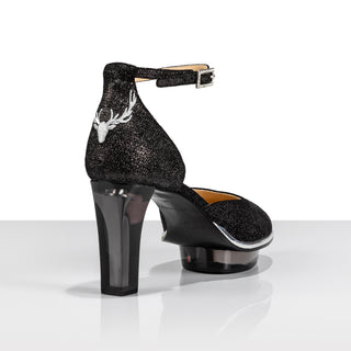 Ein zauberhafter Dirndlschuh als Closetoe Riemchenpump von der Firma Cinderella’s by Marcela in strukturiertem schimmernden schwarzen Rindsleder mit eleganter Hirschgeweihstickerei sowie hochwertigem transparentem schwarzen Absatz und Plateau. Die Schuhe sind mit silbernen Accessoires verziert, und die Schnalle ist mit funkelnden Steinchen veredelt. Perfekt geeignet für Oktoberfest- oder gehobene Trachtenevents.